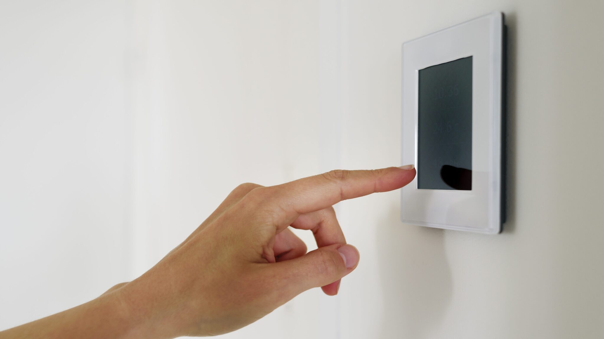 Hand using controller panel with display at home. Smart house system