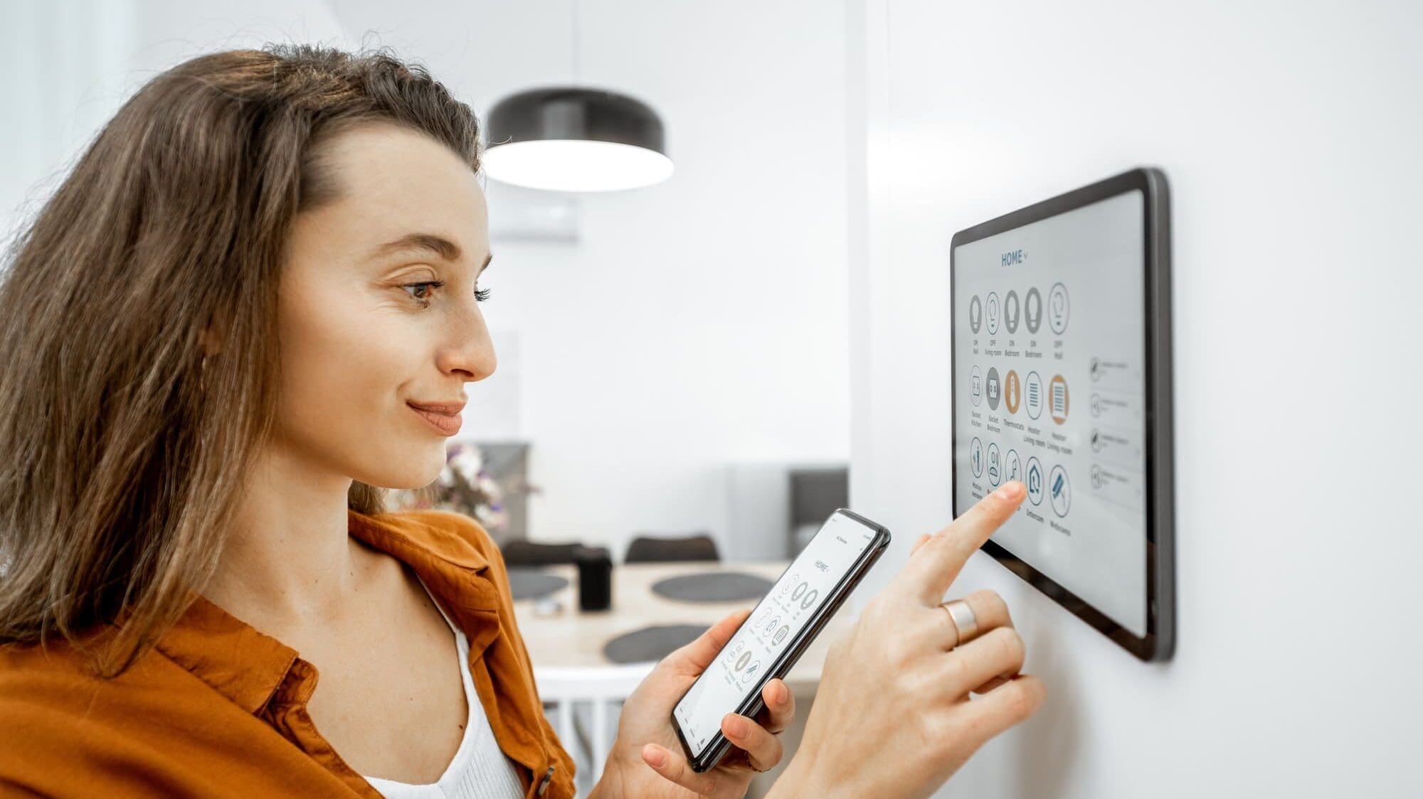 Woman controlling smart devices with a digital tablet at home