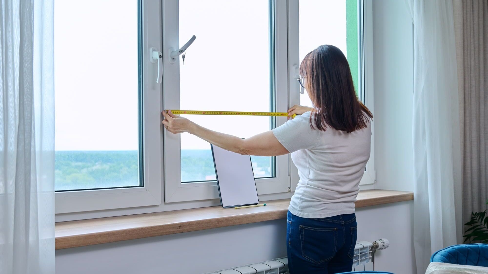 Woman measuring window with tape measure, tailoring service with step-by-step guide to configuring automated shades