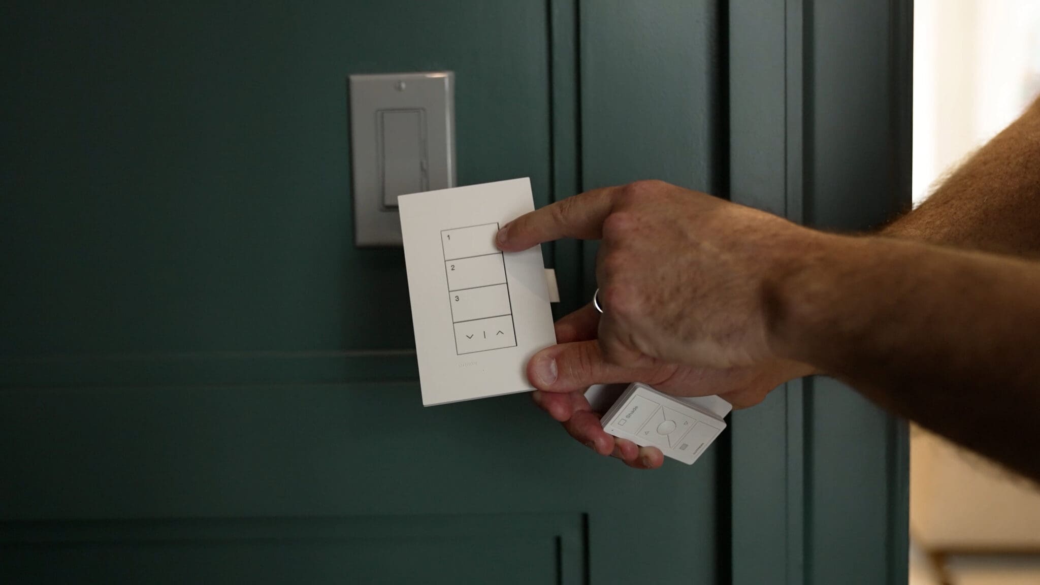 Lutron Pico remote and keypad on a green paneled wall