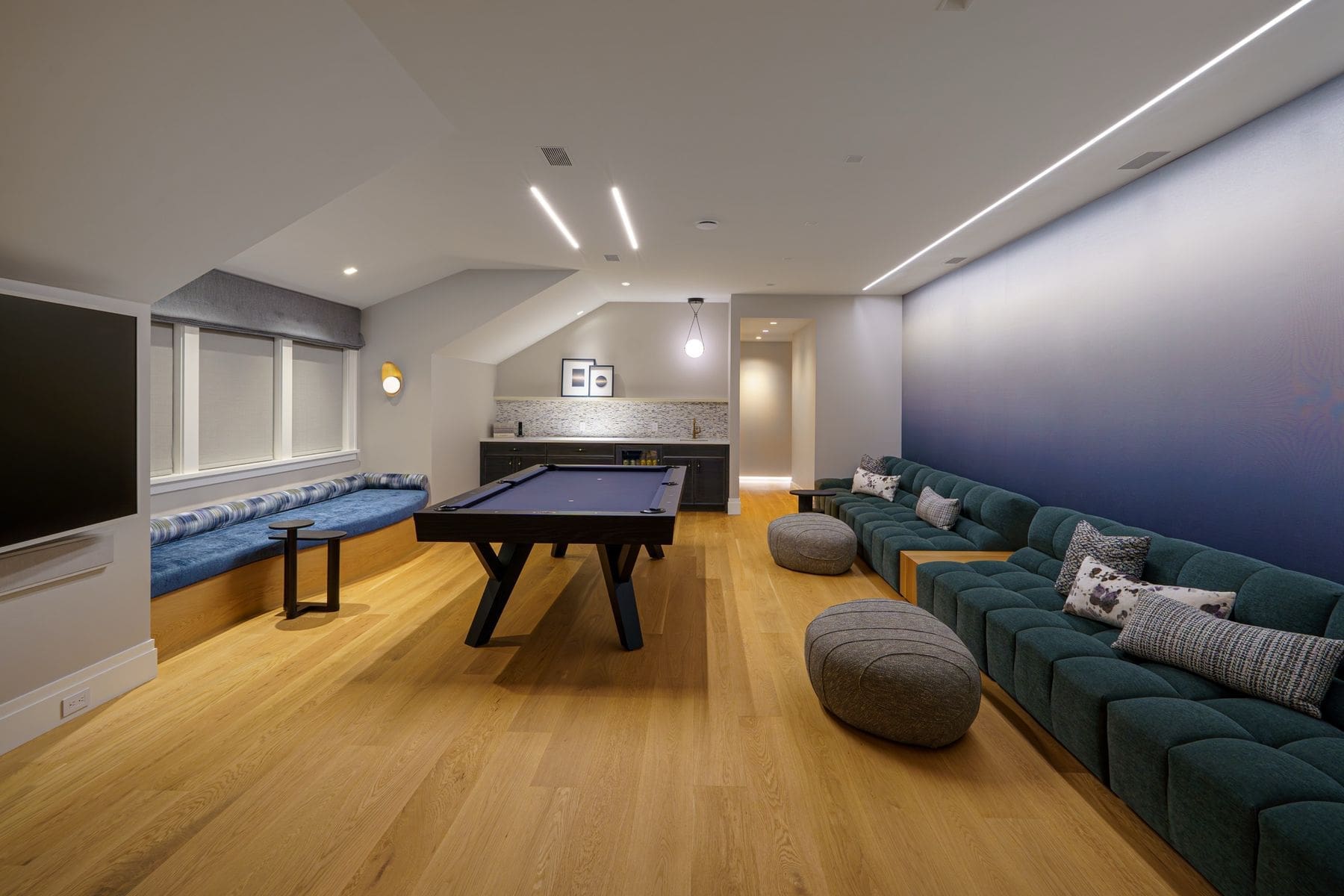 Game room with billiards table, tufted sectional, linear cove lighting and wall-mounted display