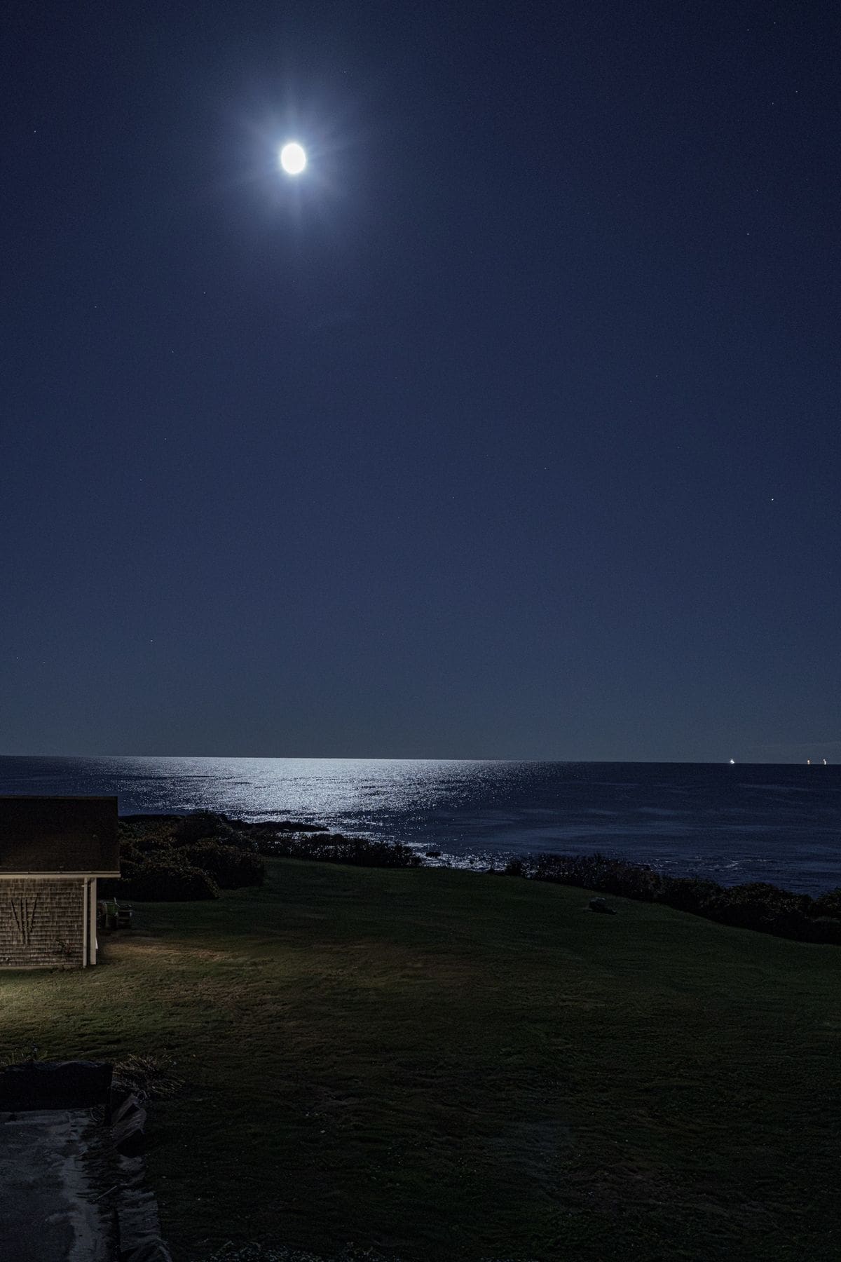 Full moon over the Atlantic with moonlight reflected on the water beside a Rhode Island oceanfront residence