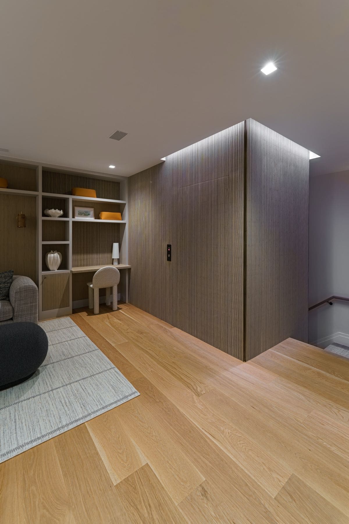 Upper landing with built-in shelving and reeded wood elevator enclosure